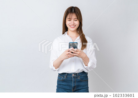 Studio shot of Beautiful Asian businesswoman holding smartphone and smiling on white background. 102333601