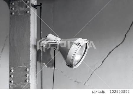 Minimal Industry style grey metallic lighting lamp on gray pillar and cracked wall background. Industrial building interior concept with copy space. 102333892