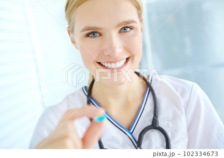 Take two of these twice a day. Portrait of a pretty nurse holding up a blue pill. Take two of these twice a day. Portrait of a pretty nurse holding up a blue pill. 102334673