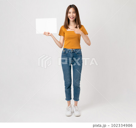 Happy young Asian woman holding a blank paper with smiling face and looking at the pink background. 102334986