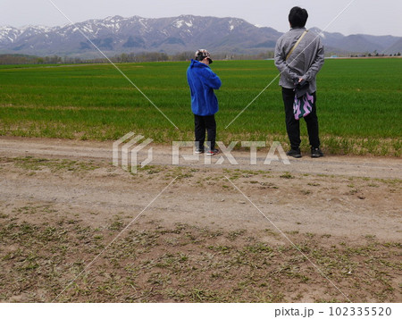雪残る春の山を眺める親子(後ろ姿) 102335520