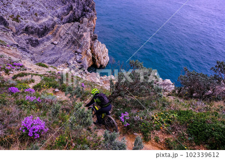 Unrecognisable mountain biker descends on a challenging trail steep towards the sea, Finale Ligure, Italy Unrecognisable mountain biker descends on a challenging trail steep towards the sea, Finale Ligure, Italy 102339612