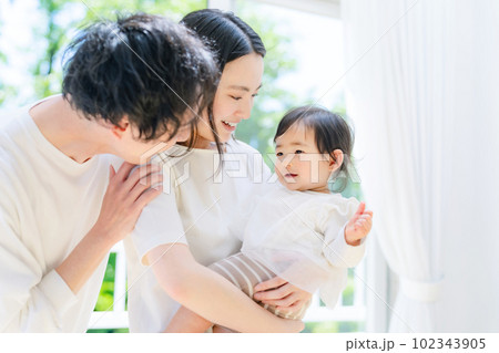 新緑の前で赤ちゃんを抱っこする両親 102343905