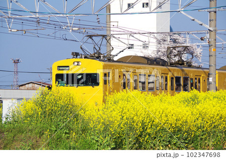 駅を発車した黄色い電車の車体が線路脇に咲いた背の高い菜の花で半分隠れている構図 駅を発車した黄色い電車の車体が線路脇に咲いた背の高い菜の花で半分隠れている構図 102347698