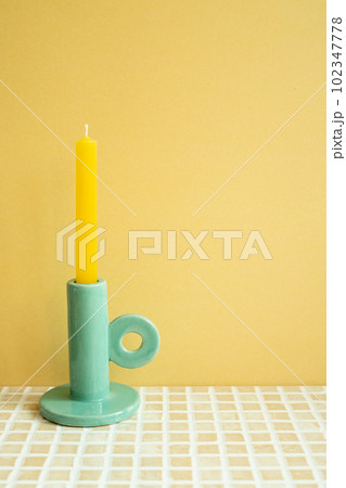Candle on check tile table. yellow wall background. home interior 102347778