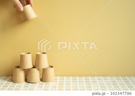 Pyramid stack of brown cup on desk. yellow background. business develop achievement growth concept 102347786