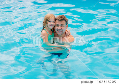 Dad and daughter play in the pool. dad hugs his daughter 102348205