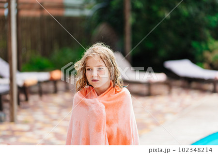 Cute teenage girl with wet hair and in a towel after swimming in the pool.  102348214