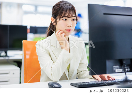 オフィスでパソコンを使って仕事をする若い女性 102350328