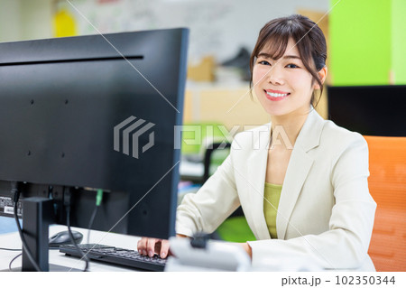 オフィスでパソコンを使って仕事をする若い女性 102350344