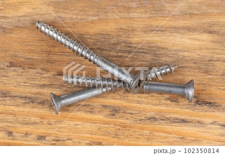 Top view of three steel screws on a wooden background. Top view of three steel screws on a wooden background. 102350814