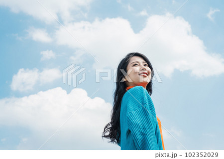 笑顔で青空を見上げる20代の女性 102352029