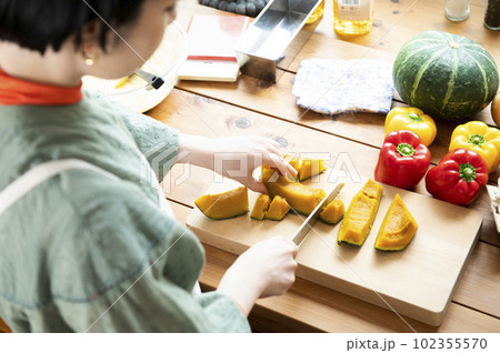 レンチンしたカボチャを包丁で切る女性 102355570