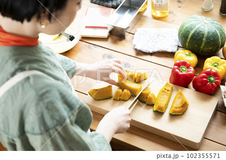 レンチンしたカボチャを包丁で切る女性 102355571