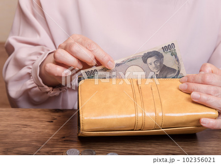 【長財布から1000円札を出す主婦】 102356021
