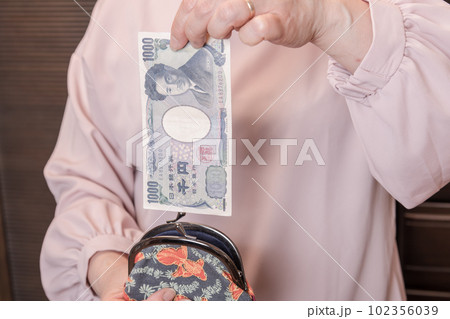 【がま口から1000円札を出す主婦】 【がま口から1000円札を出す主婦】 102356039