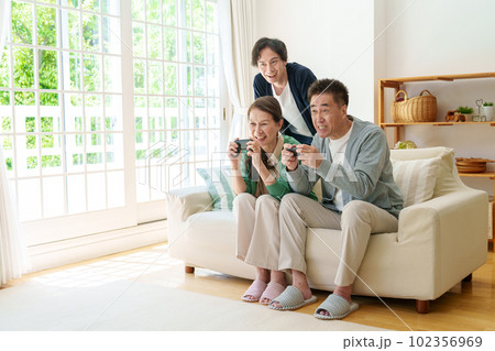 リビングでテレビゲームをプレイするシニア夫婦 リビングでテレビゲームをプレイするシニア夫婦 102356969