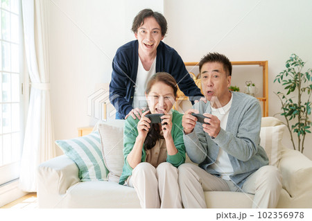 リビングでテレビゲームをプレイするシニア夫婦 102356978