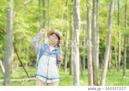 新緑の中でハイキングするシニア女性の写真 102357227