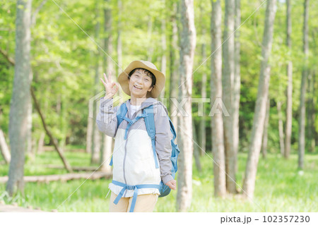 新緑の中でハイキングするシニア女性の写真 102357230