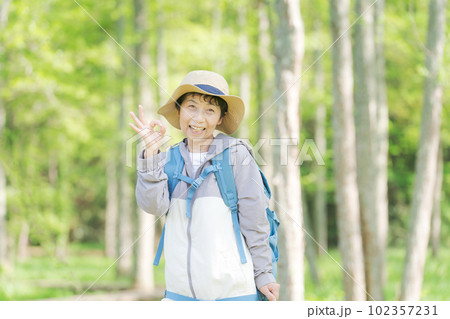 新緑の中でハイキングするシニア女性の写真 102357231
