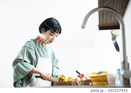 レンチンしたカボチャを包丁で切る女性 102357935