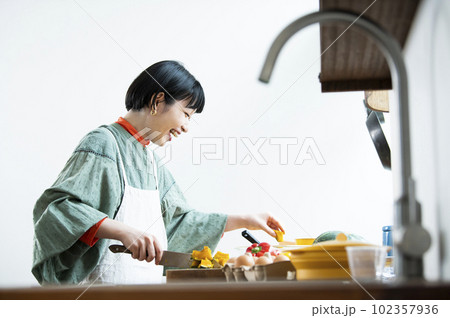 レンチンしたカボチャを包丁で切る女性 102357936