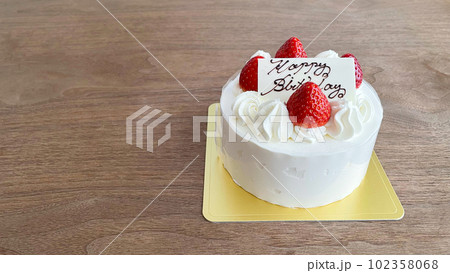 テーブルに置かれた誕生日用ホールケーキ 102358068