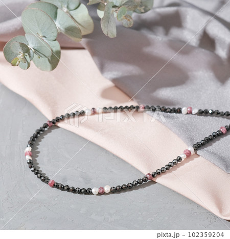 close up view of seed bead necklace on silk fabric background. handmade choker boho style 102359204