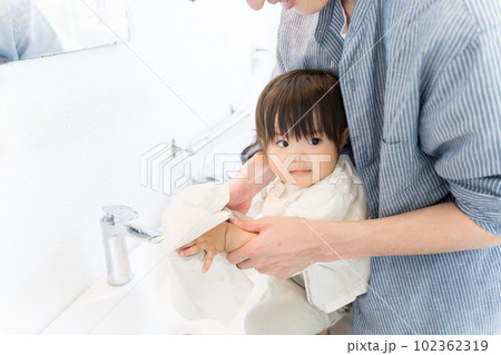 パパに、お手洗いで洗った手をペーパータオルで拭いてもらっている幼児 102362319