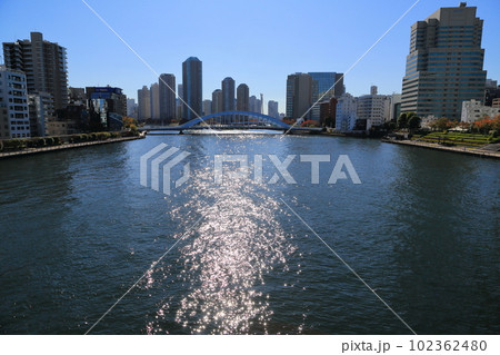 逆光に輝く隅田川の水面と高層ビル群 102362480