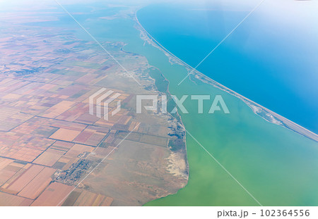 View from the airplane window at a beautiful blue clear sky, earth, sea and the airplane wing View from the airplane window at a beautiful blue clear sky, earth, sea and the airplane wing 102364556
