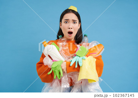 Sad asian woman holding garbage, empty plastic bottles and waste, tired of recycling, sorting rubbish, isolated on blue background Sad asian woman holding garbage, empty plastic bottles and waste, tired of recycling, sorting rubbish, isolated on blue background 102367145