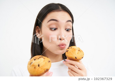 Close up portrait of asian girl eats cupcakes with happy face, isolated on white background 102367329