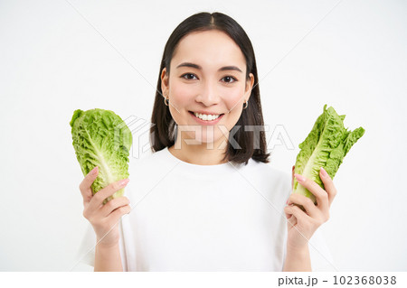 Happy korean woman vegetarian, smiling and showing cabbage, eating lettuce on diet, leads active lifestyle, white background 102368038