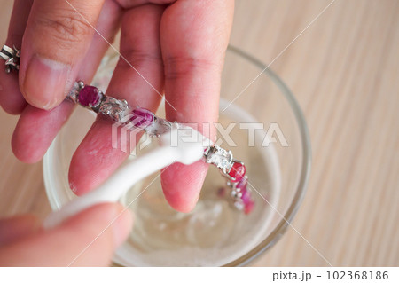 Jeweller hand cleaning and polishing vintage jewelry red ruby bracelet closeup Jeweller hand cleaning and polishing vintage jewelry red ruby bracelet closeup 102368186