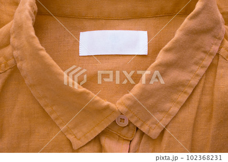 White blank clothing tag label on brown linen shirt fabric texture background White blank clothing tag label on brown linen shirt fabric texture background 102368231