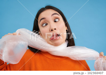 Woman suffocating, being choked by plastic bag, concept of ecology, environment and recycling, blue background Woman suffocating, being choked by plastic bag, concept of ecology, environment and recycling, blue background 102368407