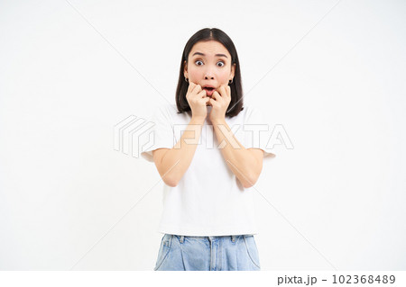 Portrait of scared woman, gasping and looking startled at camera, worried of smth, standing over white background 102368489
