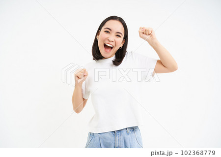 Enthusiastic asian woman, chanting, celebrating victory, rooting for team, standing excited over white background Enthusiastic asian woman, chanting, celebrating victory, rooting for team, standing excited over white background 102368779