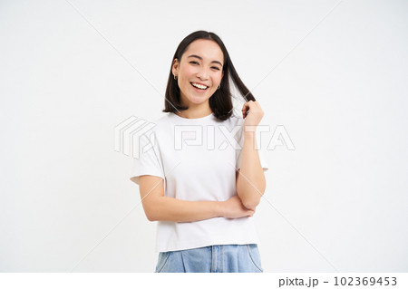 Young enthusiastic korean woman, looks with confidence, stands in power pose and smiles, white background 102369453