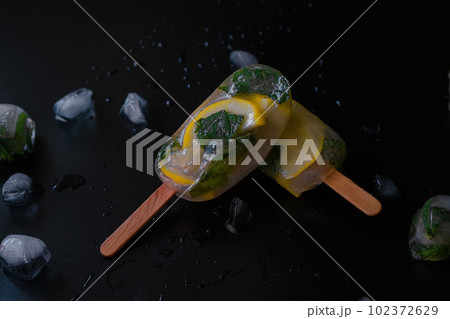 Lemon Infused Fruit Ice on a Black Background Lemon Infused Fruit Ice on a Black Background 102372629