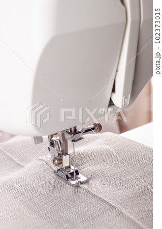 Modern sewing machine presser foot with linen fabric and thread, closeup Modern sewing machine presser foot with linen fabric and thread, closeup 102373015
