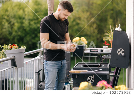 Man use fire briquettes for lighting a fire in the grill. Outdoor barbecue on terrace 102375918