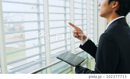 建物で指さし確認するビジネスマン 102377715