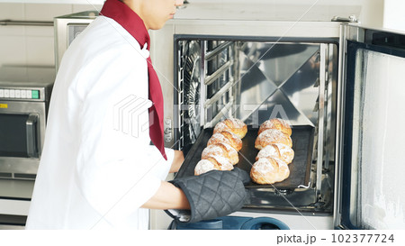 オーブンからパンを取り出すパン職人 オーブンからパンを取り出すパン職人 102377724
