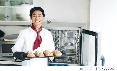 オーブンからパンを取り出すパン職人 102377725