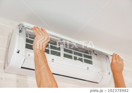 A man replaces and cleans the air cleaner filter from the air conditioner. A man replaces and cleans the air cleaner filter from the air conditioner. 102378982