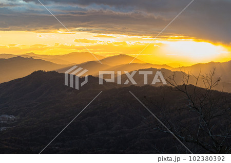 日本　京都府宮津市にある成相山パノラマ展望台から夕焼け空と山々を照らす光芒 102380392