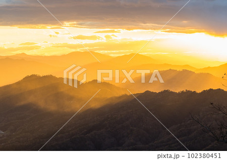 日本　京都府宮津市にある成相山パノラマ展望台から夕焼け空と山々を照らす光芒 102380451